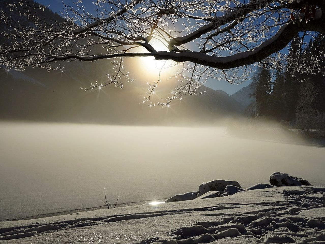 Sol baixo iluminando a superfície congelada do lago nas montanhas